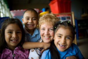 BCBS volunteers posing with children in classroom.